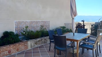 Een terras buiten met een tafel, stoelen, een bak uit baksteen en een decoratieve muur.