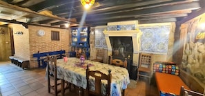 A rustic interior with a wooden table, chairs, a clock, and a blue cabinet.