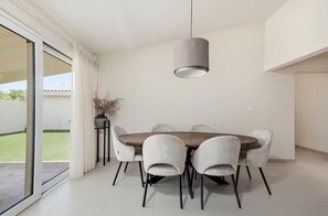 A dining area with a round table, six chairs, and a pendant light. - Modern 4BR Palm Beach Home | Garden & BBQ (Noord)