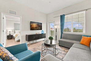 Een moderne woonkamer met een bank, stoelen, een salontafel en een televisie.