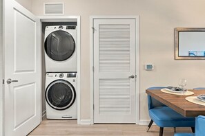 A laundry room with two washing machines and a dryer, a dining area with a table and chairs, and a closed door. - Vista Cay 3BR Condo • Pools • Near Universal (Orlando)