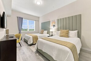 Een hotelkamer met twee bedden, een bureau, een stoel, een televisie en een raam met gordijnen.