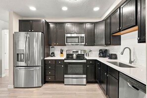 A modern kitchen with stainless steel appliances, dark cabinetry, and a white countertop. - Vista Cay 3BR Condo • King Suite • Near Universal (Orlando)