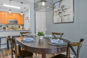 A dining area with a round table set for four, surrounded by wooden chairs. - Vista Cay 3BR Condo • Pools • Near Universal (Orlando)
