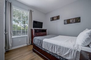 A bedroom with a bed, a TV on a dresser, and a window with blinds. - Vista Cay 3BR Condo • King Suite • Near Universal (Orlando)