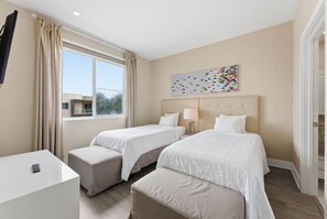 Ein Hotelzimmer mit zwei Betten, einem Schreibtisch und einem fensterbepflanzten Fenster.