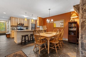Une cuisine moderne avec des meubles en bois, un îlot central et un coin repas comprenant une grande table et des chaises.