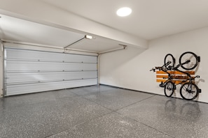 Eine saubere, leere Garage mit geschlossenem Garagentor, einer Deckenleuchte und einem an der Wand befestigten Fahrradständer.