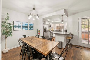 A modern kitchen with a central island, stainless steel appliances, and a dining area with a wooden table and chairs. - Walk to Snow Summit Condo | Hot Tub | Fireplace (Big Bear Lake)