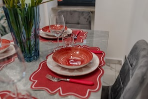 A dining table set with red plates, clear glasses, and a red napkin. - Maison Tresor by Wonderful Italy (Turin)