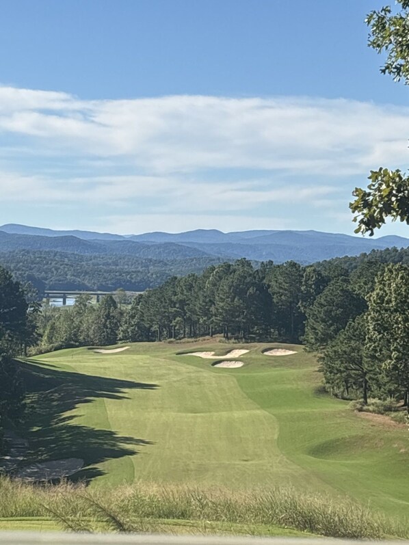 A golf course with a clear view of the surrounding landscape, including distant hills and a body of water. - Currahee Club Spacious 2BR Condo • Golf, Lake and Mountain Retreat (Toccoa)