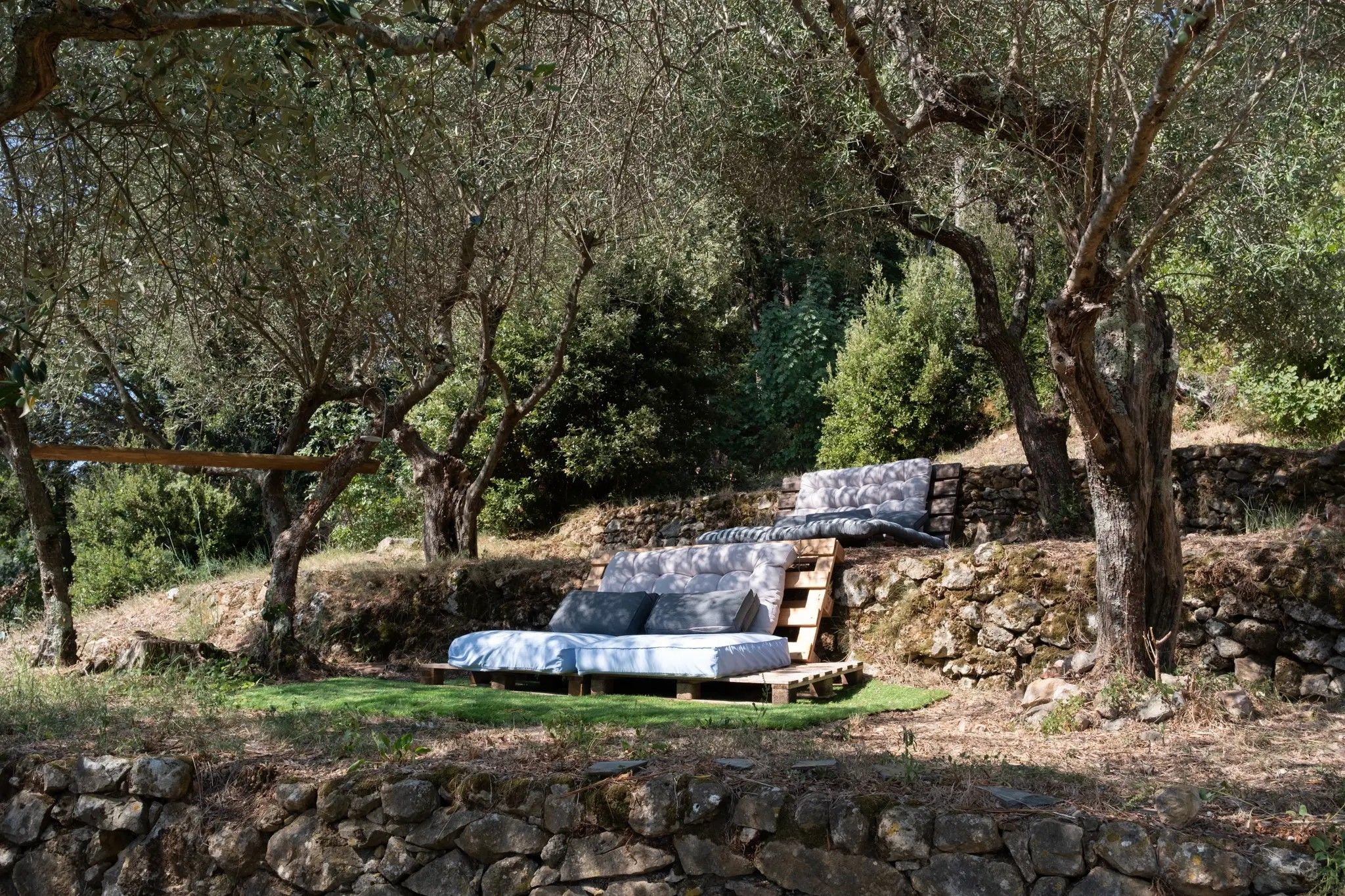 A rustic outdoor seating area with a wooden bench and a cushioned bench.
