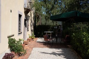 A patio with a table and chairs, surrounded by potted plants and a barbecue grill. - The Bauhaus Room - Lucca Countryside (Lucca)