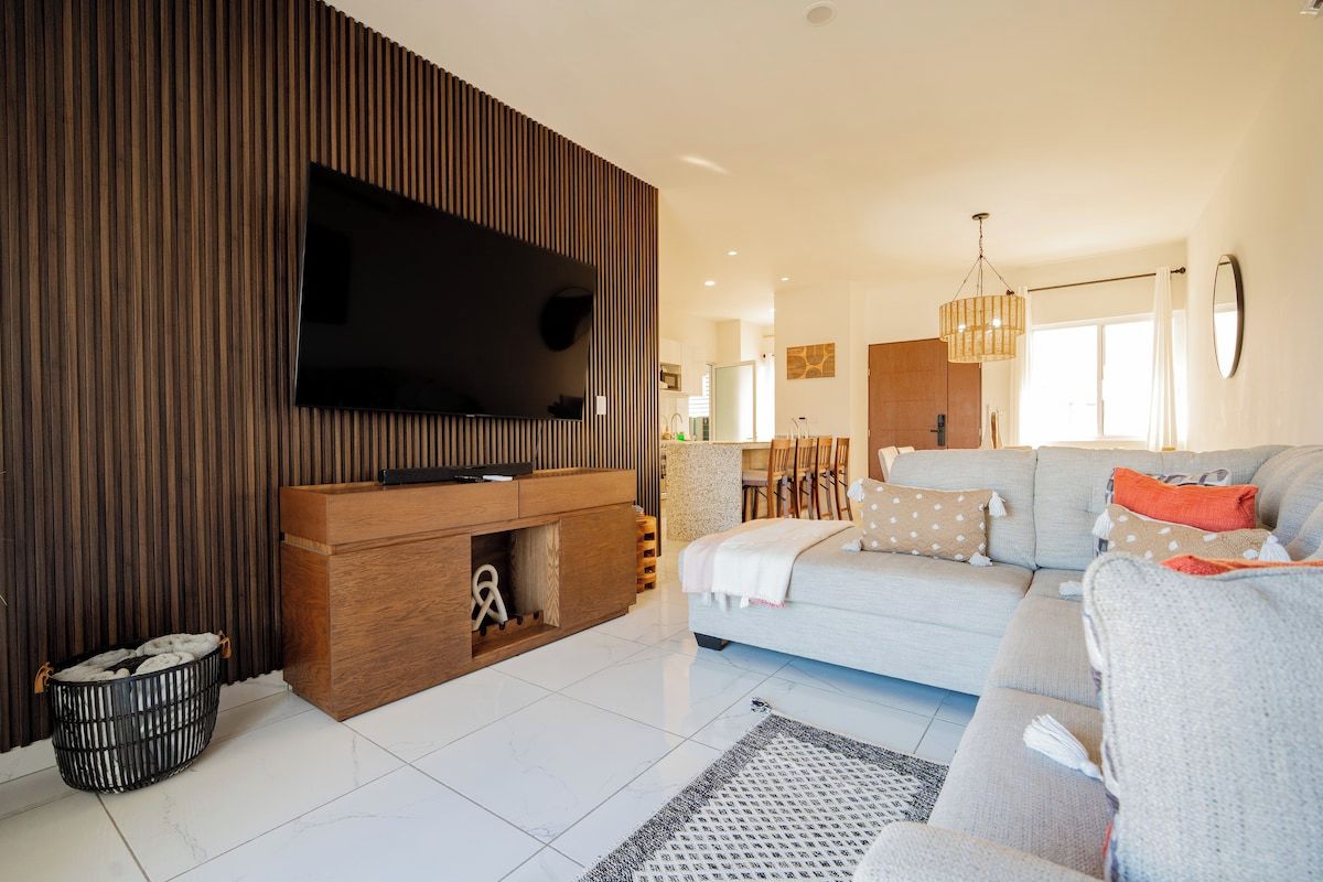 Uma sala de estar moderna com televisão de tela plana, um sofá e um espaço de jantar.