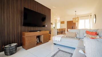 Uma sala de estar moderna com televisão de tela plana, um sofá e um espaço de jantar.