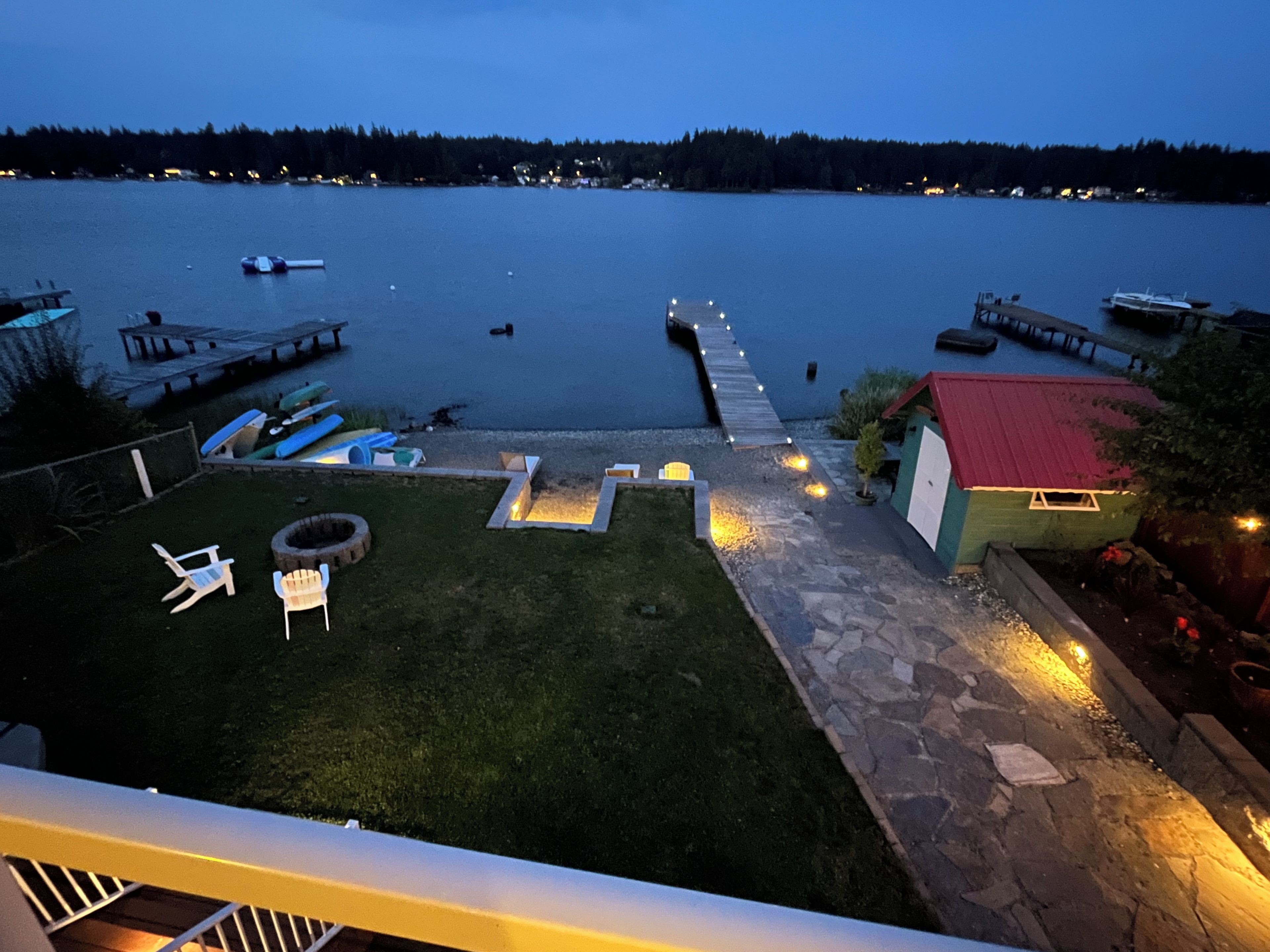 A lakeside property with a dock, outdoor seating, and a small shed.
