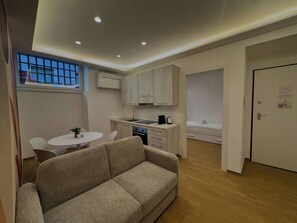 A compact living space with a kitchenette, a sofa, a dining area, and a bed. - Red Chic Colosseum - ChiacchioPM (Roma)