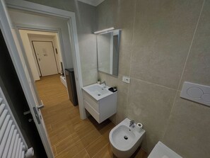 A modern bathroom with a white sink, a bidet, and a mirror. - Red Chic Colosseum - ChiacchioPM (Roma)
