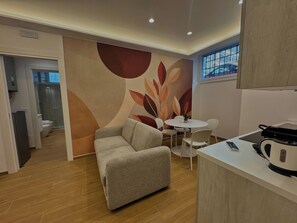 A modern kitchen with a dining area, a sofa, and a small table with chairs. - Red Chic Colosseum - ChiacchioPM (Roma)