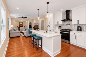 A modern kitchen with white cabinetry, a central island, and a dining area with a sofa and chairs. - Atlanta Ranch Retreat 6BR - Sleeps 16 (Atlanta)