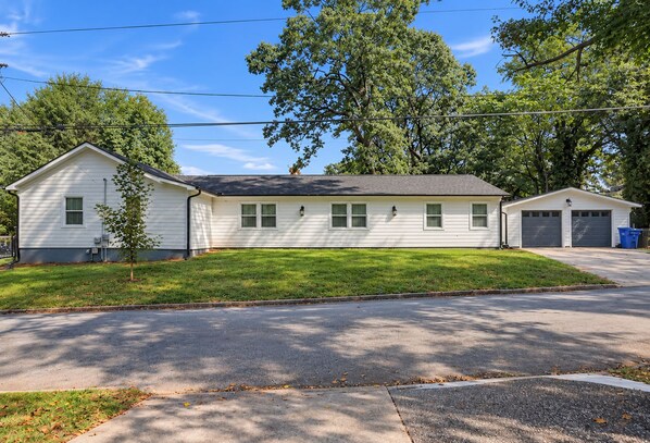 A two-story house with a garage, a small front yard, and a tree.