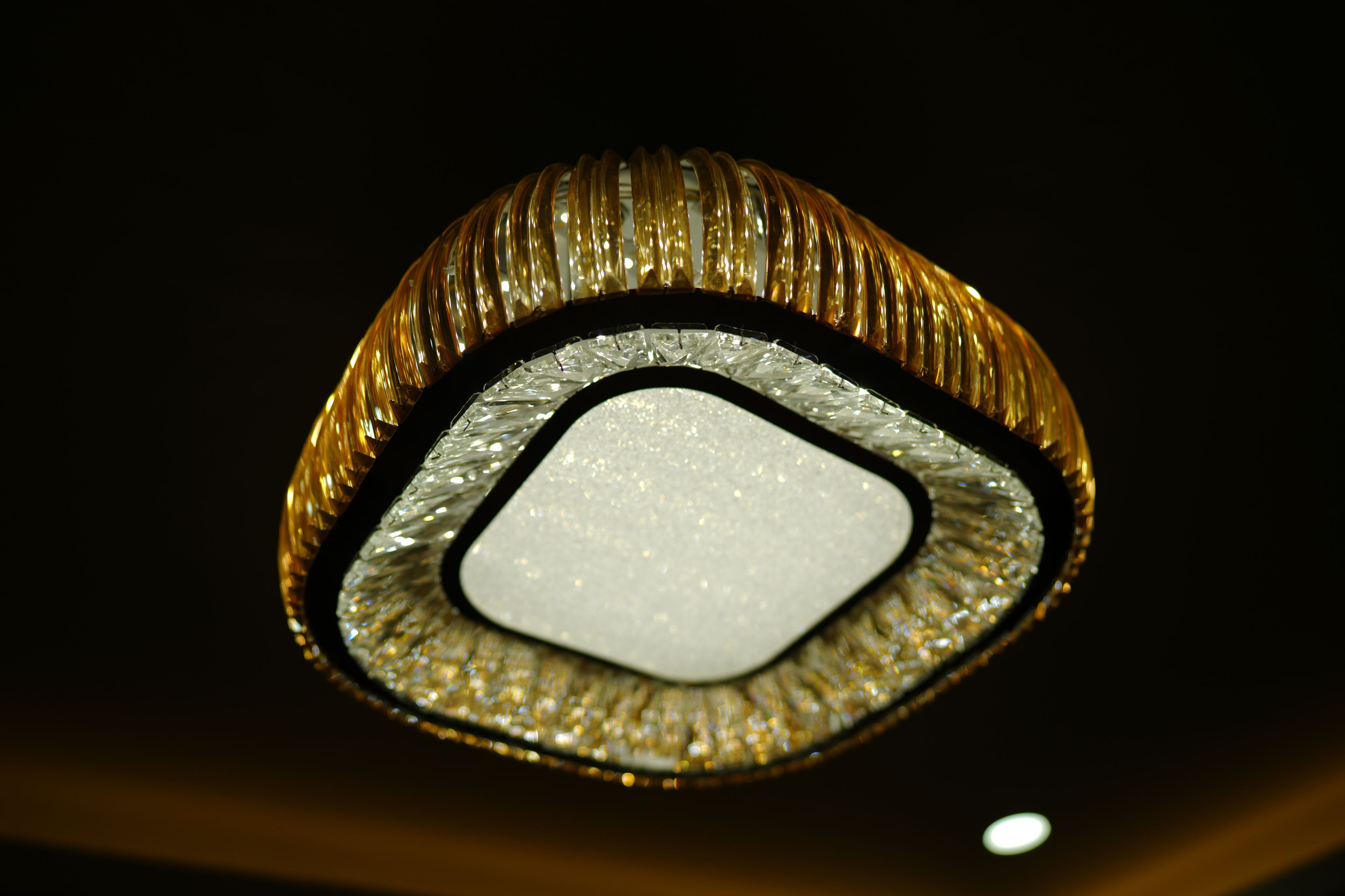 Primer plano de un accesorio decorativo de techo con una fuente de luz central y un borde metálico con diseños.