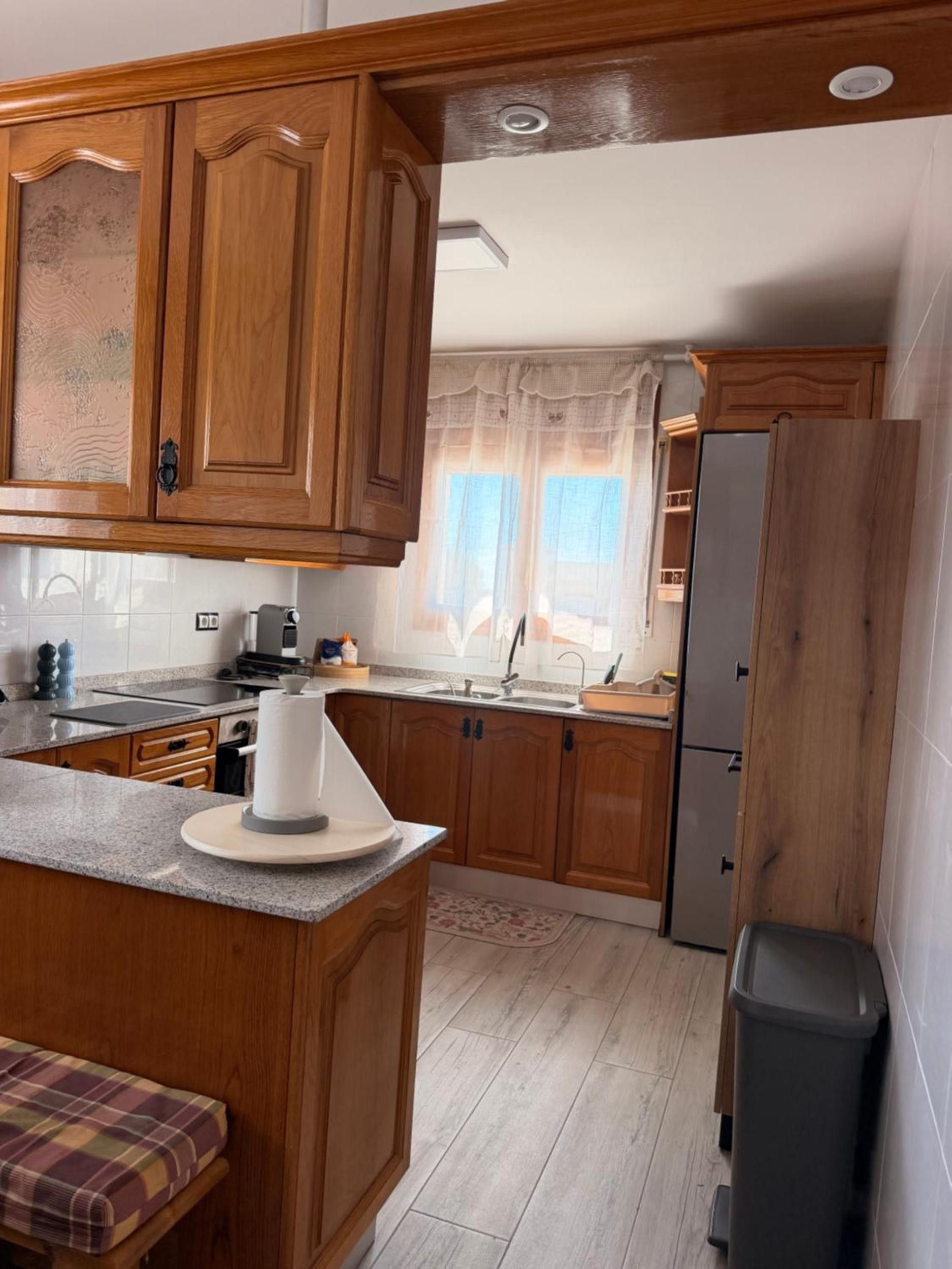 Una cucina con mobili in legno, un piano di lavoro, un lavandino e un frigorifero.