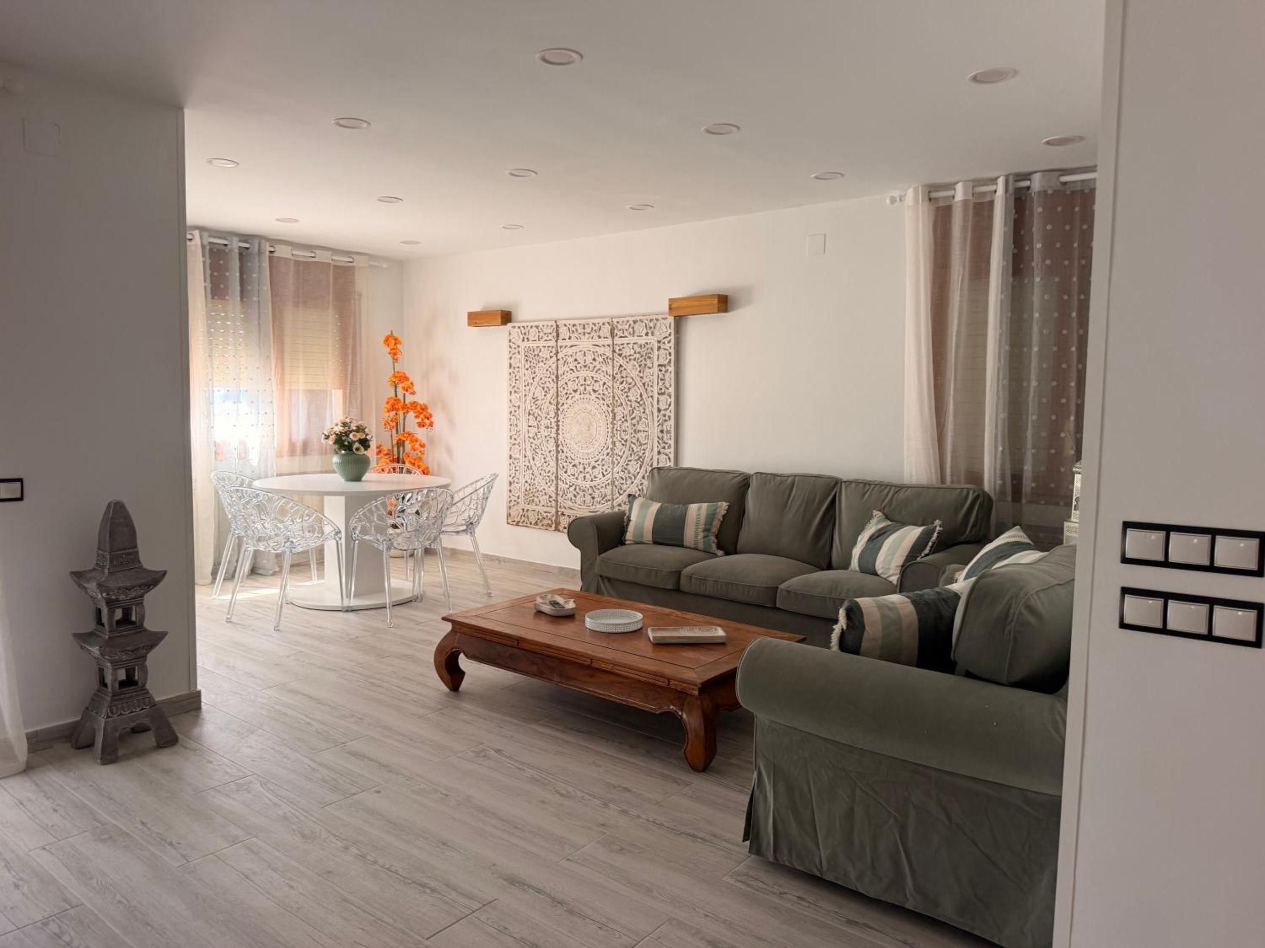 Een moderne woonkamer met een bank, salontafel en een eettafel met stoelen.