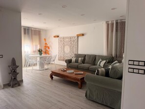 A modern living room with a sofa, coffee table, and dining table with chairs. - Villa 'Angkor' with Sea View, Wi-Fi and Air Conditioning (El Papagai)