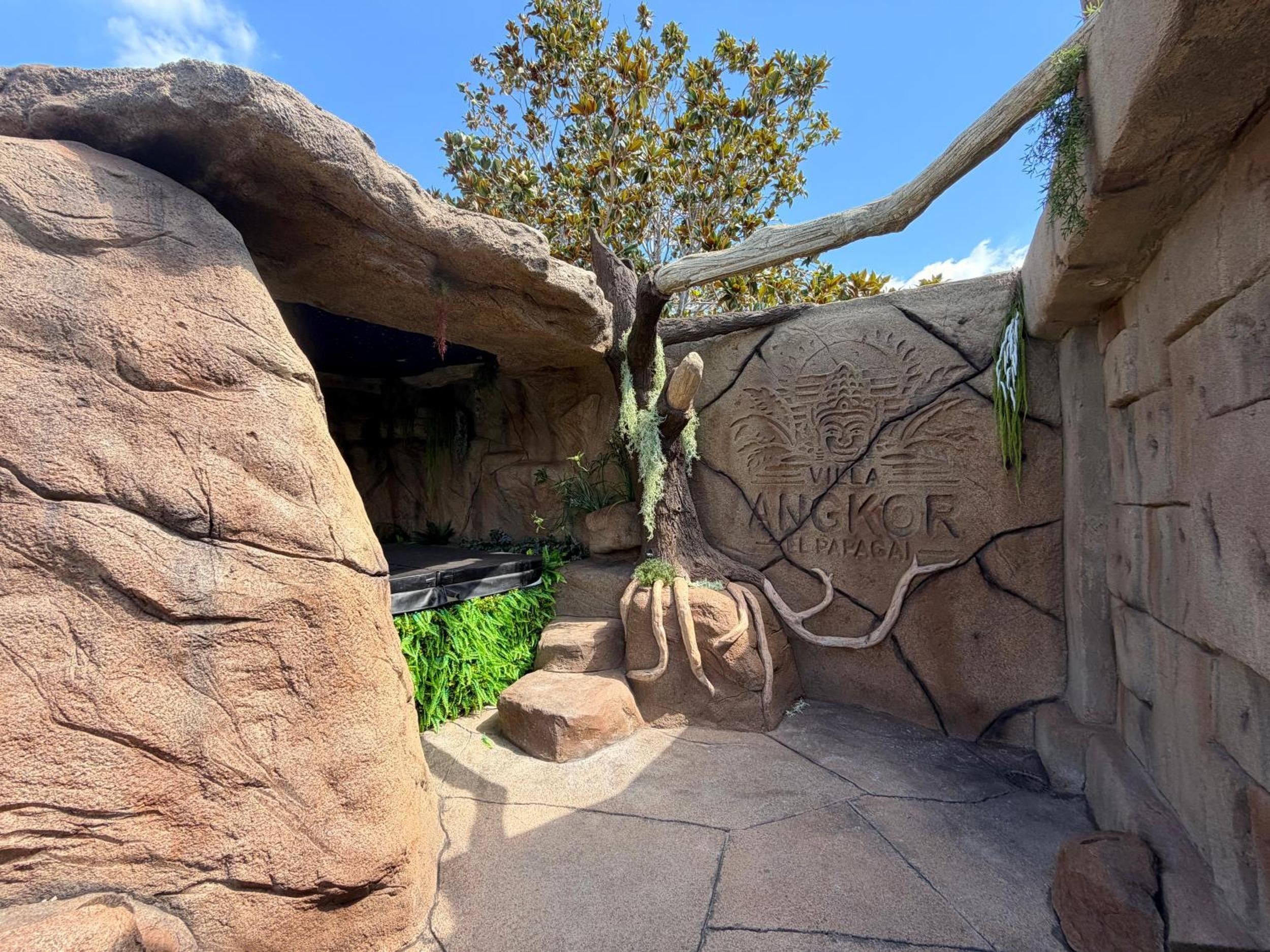 A rock formation with a carved inscription, a tree, and a small platform.