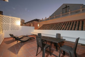 Una terrazza sul tetto con un tavolo e sedie, pavimento piastrellato e una parete decorativa.