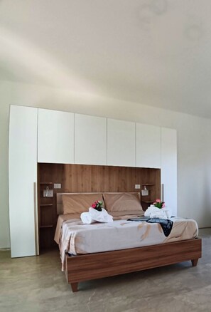 Una camera da letto con un letto in legno, un'armadio bianco e una testiera in legno.