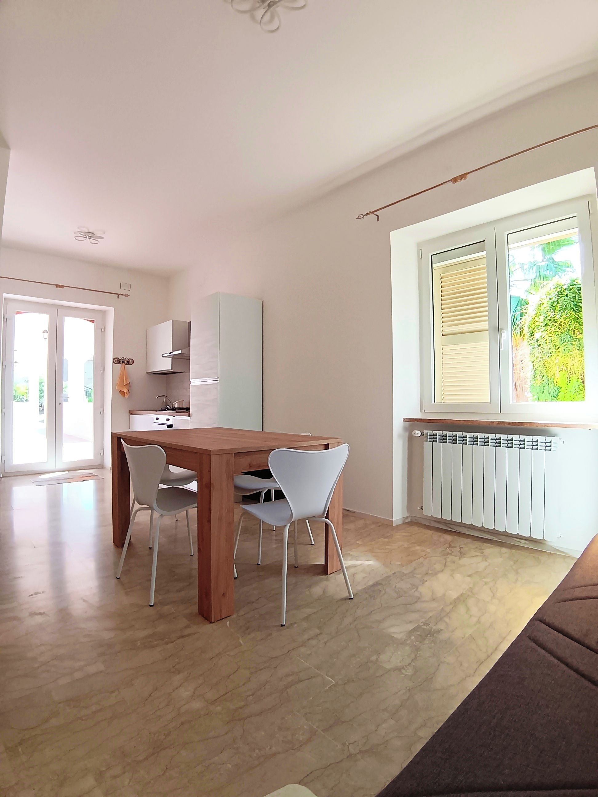 Eine moderne Küche mit Essbereich, Heizkörper und einem Fenster mit Jalousien.