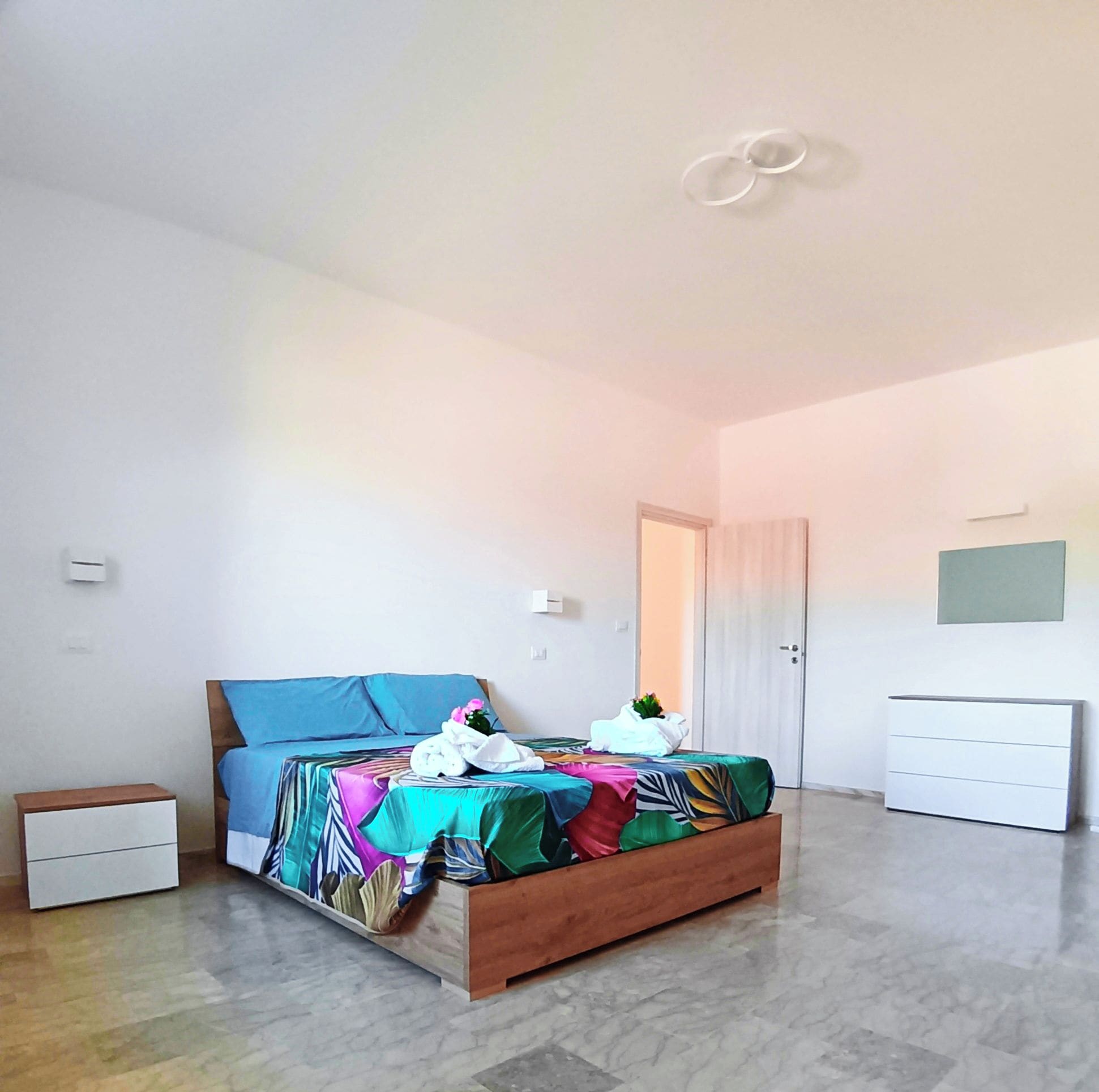 Ein Schlafzimmer mit Bett, Nachttisch, Kleiderschrank und einer Tür.