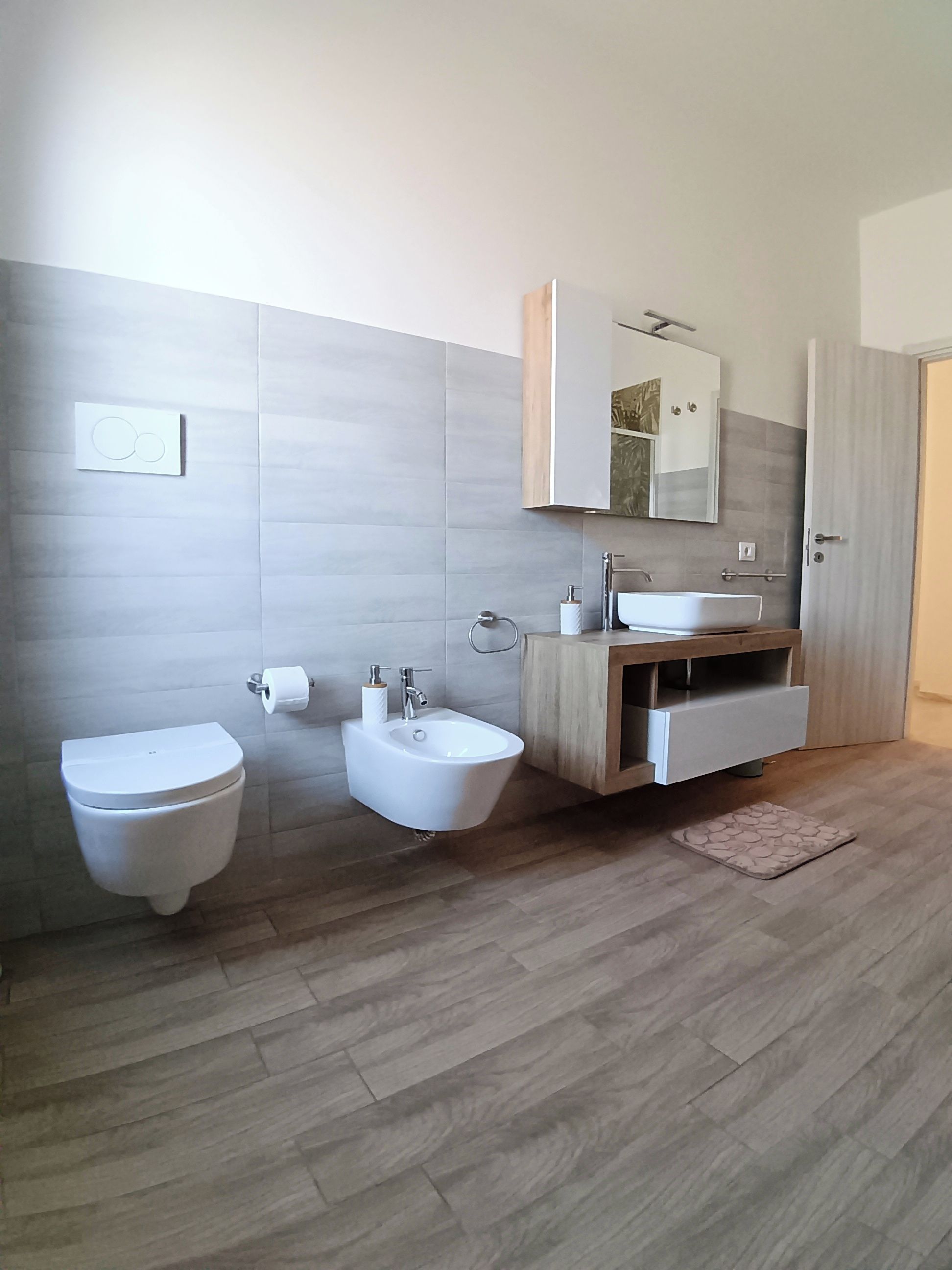 Een moderne badkamer met toilet, hygiëneschuimer en wastafel.