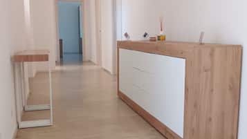 A hallway with a wooden reception desk, a marble floor, and a door at the end.