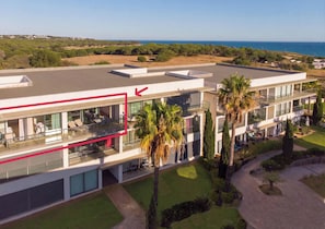 A modern multi-story hotel with a rooftop terrace, surrounded by greenery and a view of the sea. - Apartment 'Cavalo Preto' with Shared Pool, Wi-Fi and Air Conditioning (Faro)