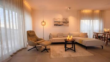 A modern living room with a sofa, armchair, and a coffee table with candles.