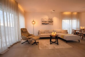 Una sala de estar moderna con un sofá, un sillón y una mesa de centro con velas.