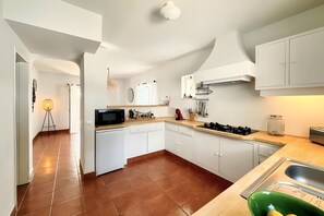 Una cocina moderna con muebles blancos, un microondas, una estufa y un lavabo.
