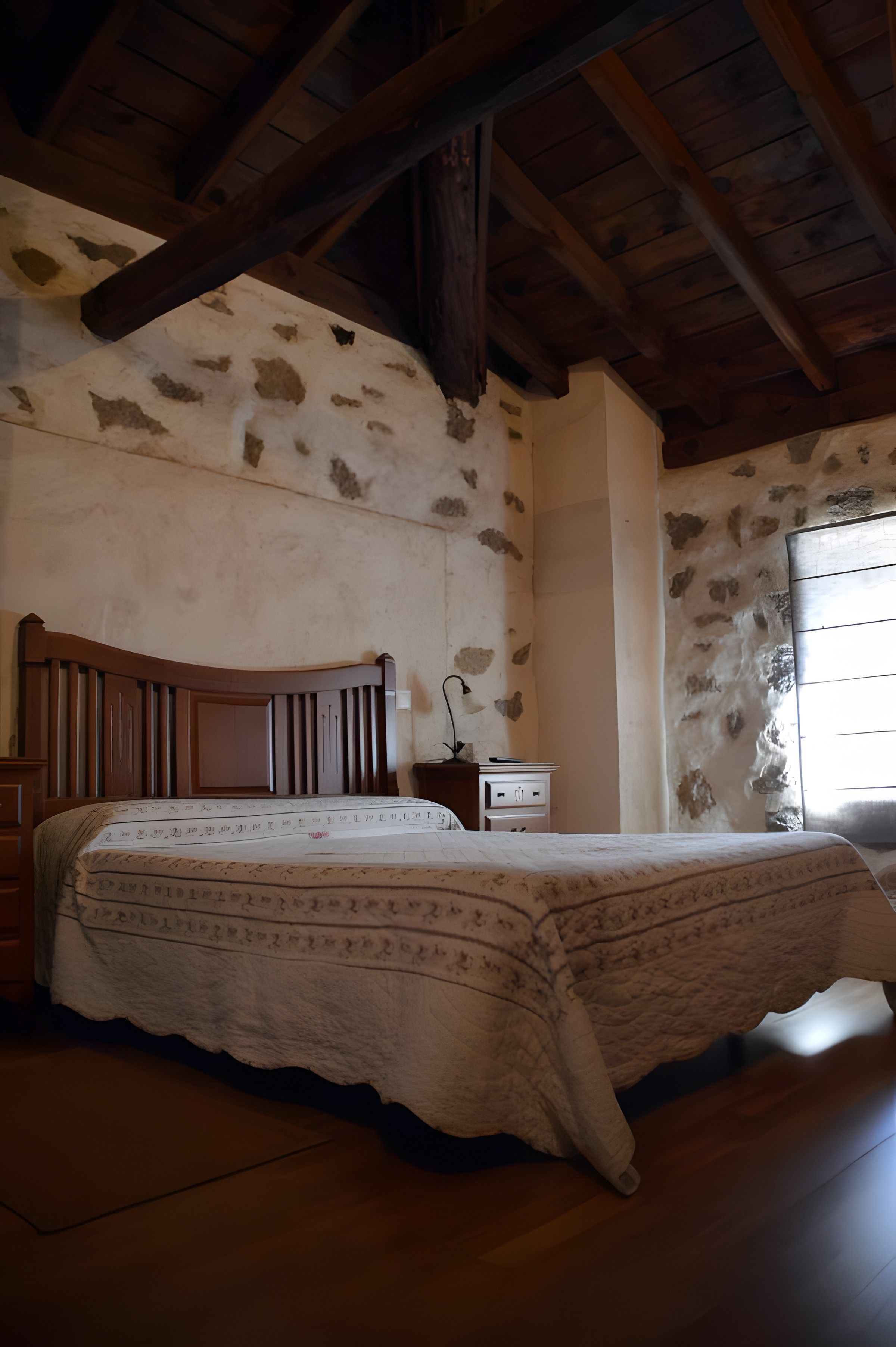 Un dormitorio con una cama de madera, una mesita de noche y una pared de piedra.