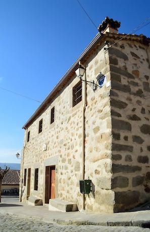 Un bâtiment en pierre doté d’une façade traditionnelle, d’une porte en bois et d’un lampadaire.