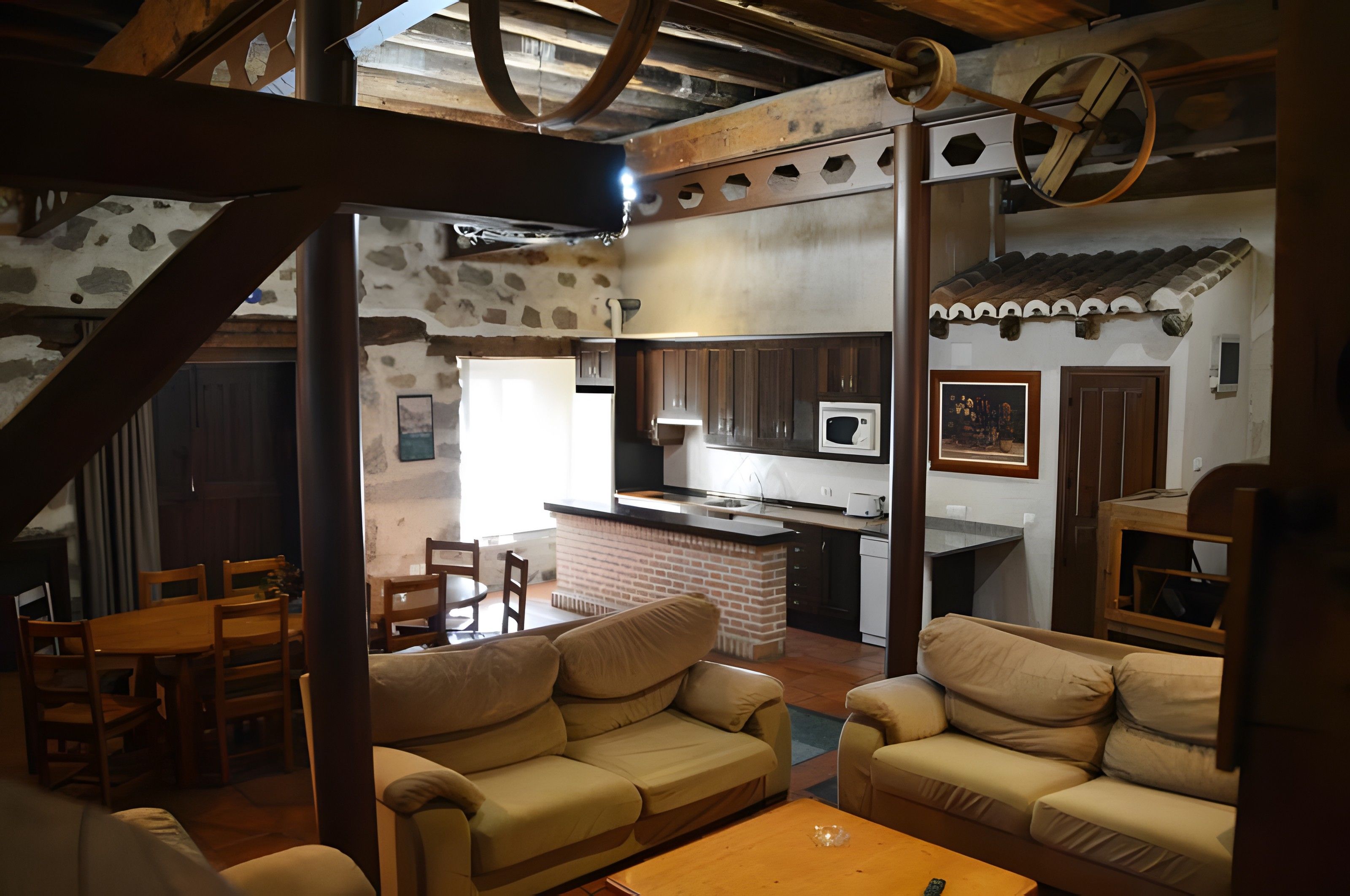 Amplia sala de estar con chimenea, cocina equipada con microondas y comedor con mobiliario de madera.