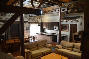 Un'ampia zona giorno con camino, una cucina con forno a microonde e una sala da pranzo con arredi in legno.