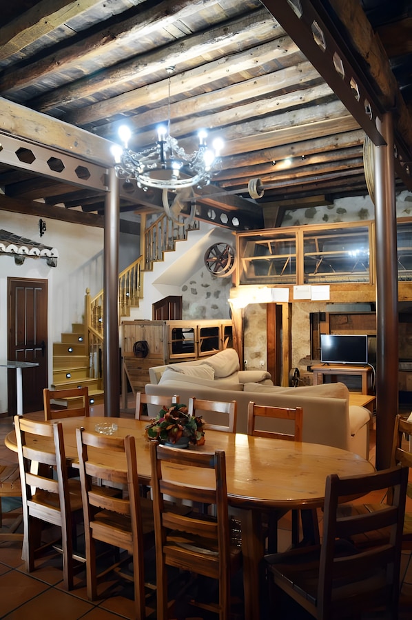 A dining area with a round table and chairs, a chandelier, and a staircase leading to an upper level.