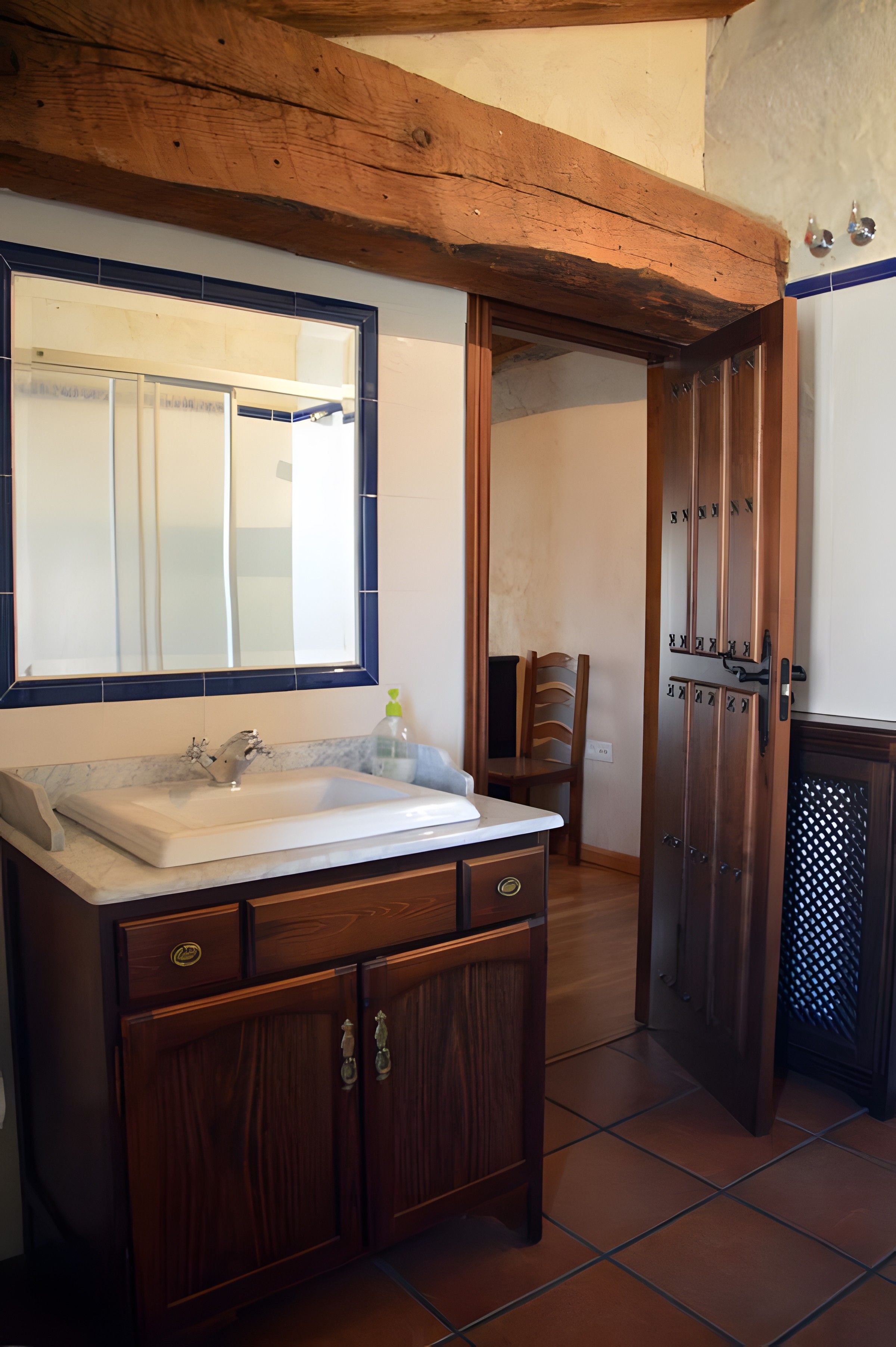 Un baño con tocador de madera, un espejo y un lavabo.