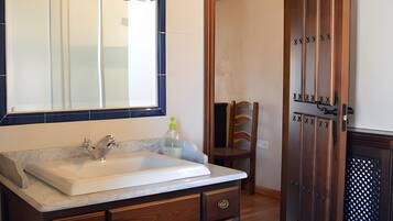 Un baño con tocador de madera, un espejo y un lavabo.