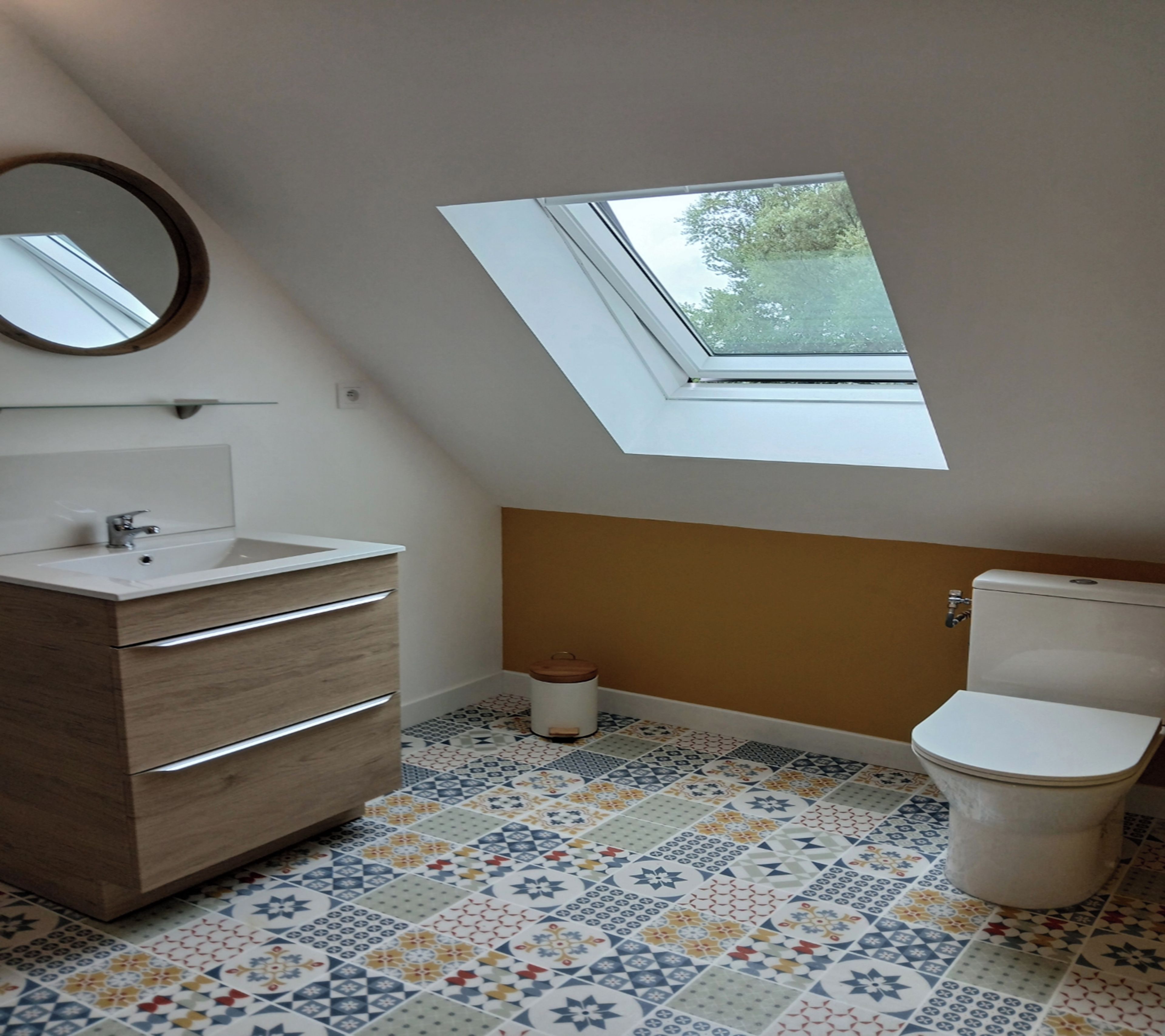 Une petite salle de bain moderne avec un puits de lumière, un meuble-lavabo en bois, des toilettes et des carreaux de sol à motifs.