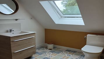 Une petite salle de bain moderne avec un puits de lumière, un meuble-lavabo en bois, des toilettes et des carreaux de sol à motifs.