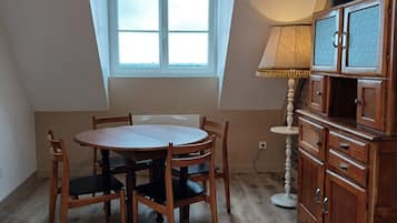 Un coin repas avec une table ronde et des chaises, une fenêtre donnant sur un beau paysage et une lampe.